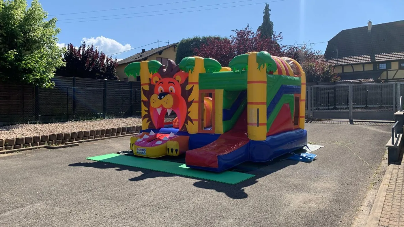 Château gonflable Lion avec toboggan installé dans un jardin en Alsace