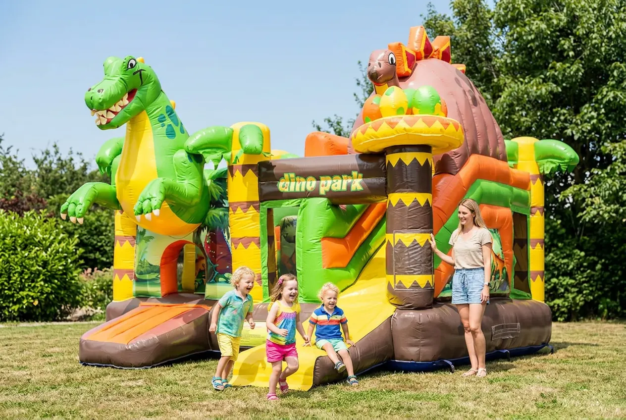 Château gonflable Dinoworld de 3,9 m de haut avec des enfants qui jouent et un adulte à côté pour comparer la taille réelle